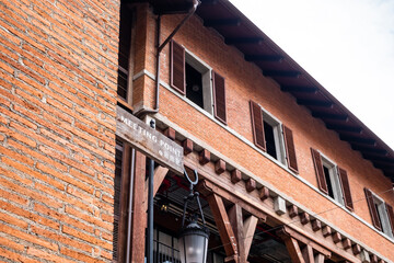 "Meeting Point" sign on wooden plank in English and Chinese languages attached to orange brick wall. Vintage building on the side.
