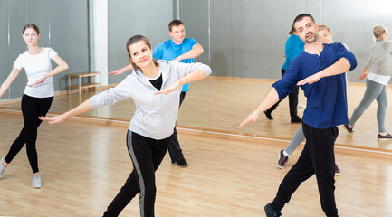 Cheerful people practicing vigorous lindy hop movements in dance class..