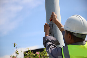 An electrician solves a power failure by wearing a helmet and protective gloves.
