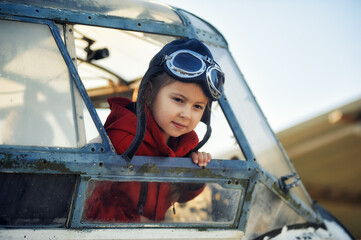Portrait of a cute little girl in the cockpit of an old plane. Childhood dreams of aviation.