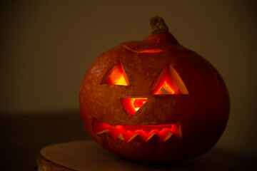pumpkin with carved eyes for Halloween. A fire flickers inside the pumpkin, and large candles burn on the table