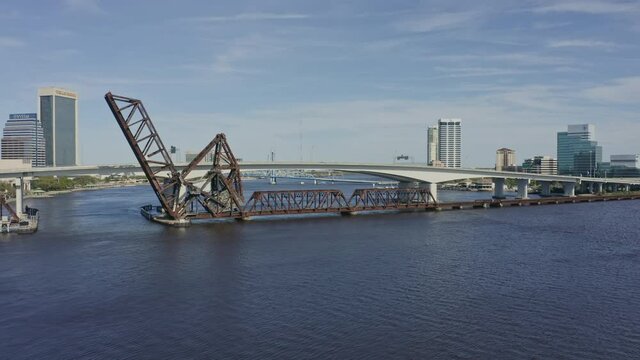 Jacksonville Florida Aerial v8 pan left shot of railroad bridge, highway bridge and traffic during rush hour - March 2020