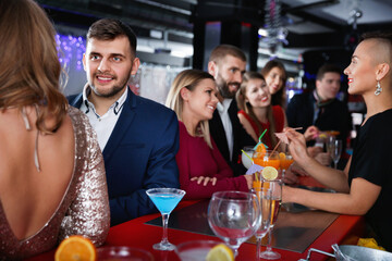 Young happy cheerful people with cocktails having fun at nightclub