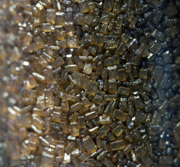 Macro golden cake decorating sugar crystals in glass cylinder