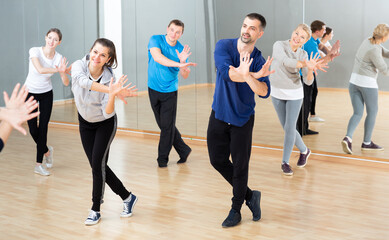 Fototapeta na wymiar Cheerful people practicing vigorous lindy hop movements in dance class.