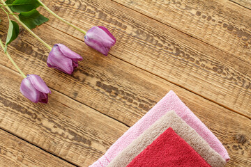 Towels and lilac tulip flowers on wooden background.