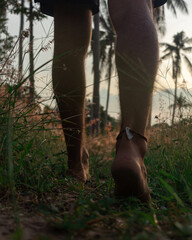 Pies de hombre caminando descalzo en isla por la naturaleza con palmeras