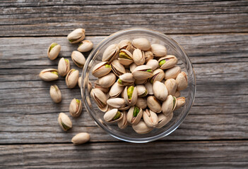 Pistachios in a bowl set against an old wooden backdrop