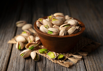 Pistachios in a bowl set against an old wooden backdrop