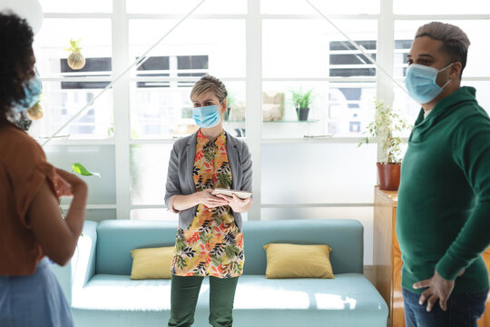 Office colleagues wearing face mask talking in office 