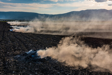 Farmers burn the dry grass and straw stubble on field in autum, another cause of global warming. Air pollution.