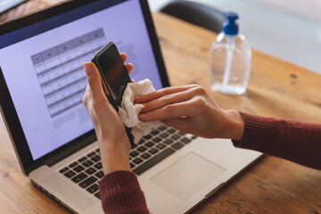 Mid section of woman wiping her smartphone with a tissue