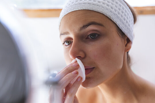 Close up of woman cleansing her face with cotton pad in bathroom