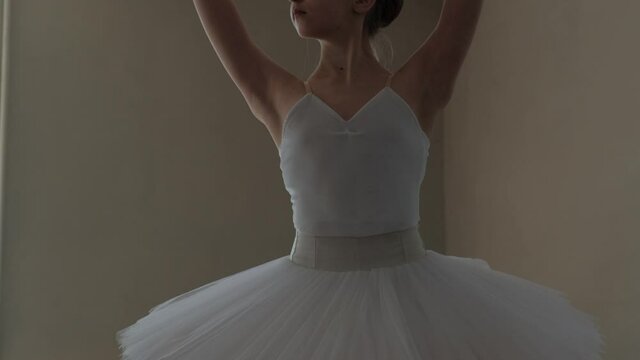 A ballerina in a white tutu trains and dances beautifully.