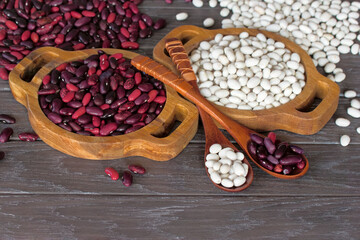 Obraz na płótnie Canvas white and red beans in wooden bowls and spoons close-up. background with raw red and white beans.