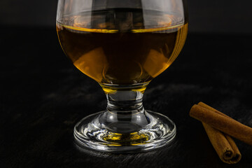 A glass of cognac and cinnamon sticks