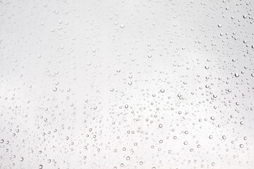 Water drop on glass window with cloudy sky on background