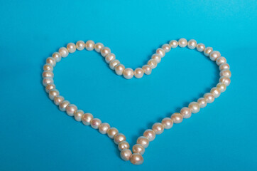 Heart-shaped pearl beads on a blue background.