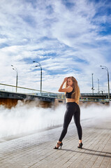 Beautiful woman dancer with long blond hair posing on city street. Female dancing improvisation -...