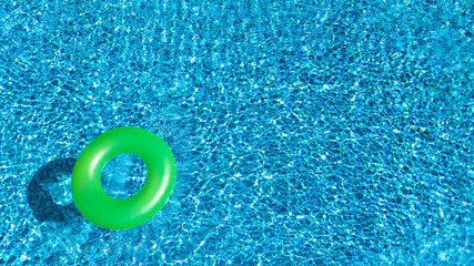 Fototapeta na wymiar Aerial view of colorful inflatable ring donut toy in swimming pool water from above, family vacation holiday resort background 