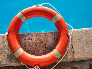 Bright, orange lifebuoy lying on the background of the pool. Concept of security, care and...