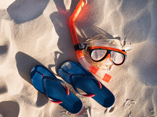 Swimming mask and flip-flops on sand background. View from above, close-up. Concept of leisure and...