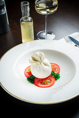 Burrata italian cheese snack with tomeatoes served on white plate