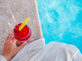 Beautiful glass with a cocktail on the background of the pool. View from above, close-up. Concept of leisure and travel
