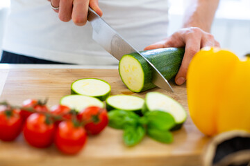Preparing healthy, vegetarian, vegan food, salad. Cutting vegetables on a wooden chopping board.