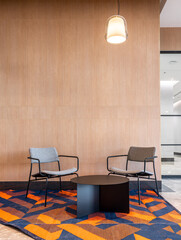 Gray fabric armchair in minimal modern style with empty wood wall background in natural light setting / interior / copy space