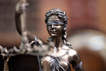 Law and justice concept. Themis sculpture in lawyers office. Bookshelf with legal books in background.