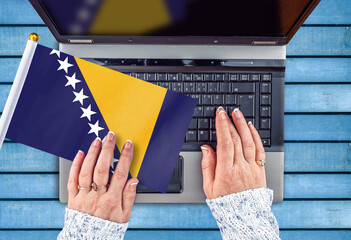 woman hands and flag of Bosnia and Herzegovina on computer, laptop keyboard 