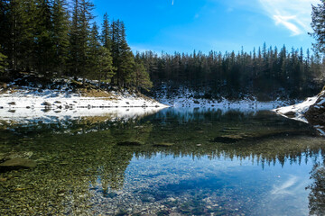 Winter landscape of Austrian Alps with Green Lake in the middle. Powder snow covering the mountains and ground. Soft reflections of Alps in calm lake's water. Winter wonderland. Serenity and calmness