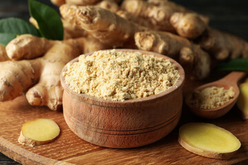 Board with ginger and ginger powder on wooden background