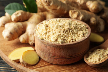 Board with ginger and ginger powder on wooden background