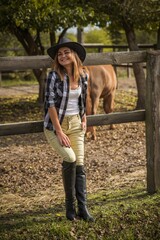 American woman on a horse farm. Portrait of girl in cowboy hat with a  horses. Hippotherapy at nature