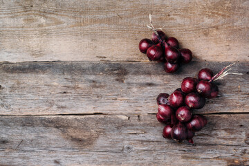 Bunch of purple onions on wooden background. Top view. Copy space. Autumn harvest