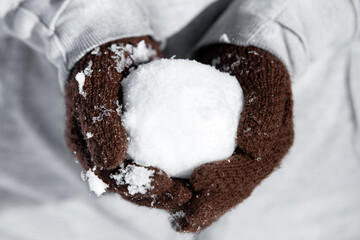 Gloves with a cold icy snowball, concept winter and funny games with snow