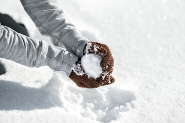 Woman forming a snowball for a funny fight, Winter game in the snow