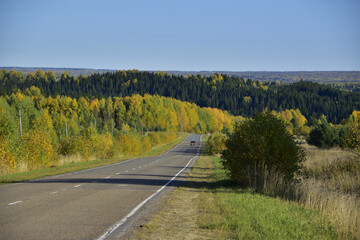 Fototapeta na wymiar Bright autumn colors of the surroundings of the highway through the Ural forests and mountains. Sunny autumn days in the foothills of the Western Urals.