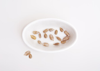 Dried sunflower seeds in white dishes isolated on white background