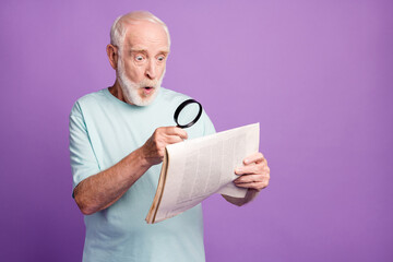 Portrait of funky shocked grey beard hair old man watching through magnifier newspaper isolated...