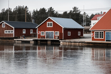 Fototapeta na wymiar Red boat house in Sweden with reflection on the ice