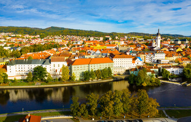 Fototapeta na wymiar Autumn landscape with Old Town of Czech city of Pisek on banks of Otava river on sunny day..