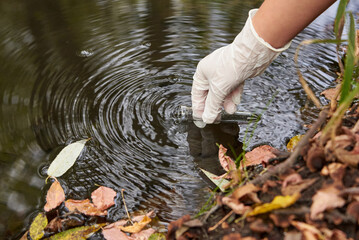 A scientist collects river water in a glass beaker.