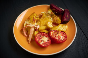 Baked potatoes with bacon, cheese and tomatoes in a plate.