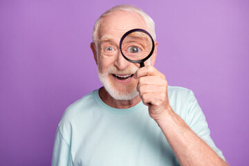 Close-up portrait of cheerful grey beard hair pensioner investigator watching through loup isolated...