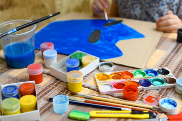 a girl drawing blue gouache cardboard, artistic creation at home, makes creative artwork