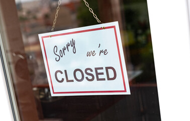 Closed sign hanging behind a store window