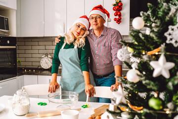 Husband and wife embrace each other beside the table at christmas kitchen